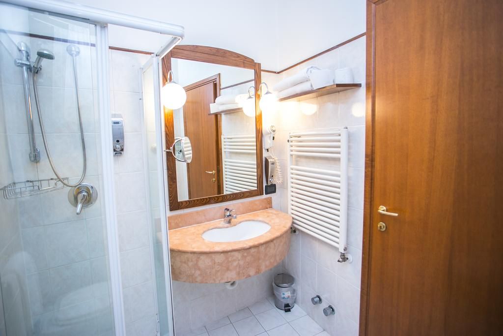 A bathroom with a glass shower enclosure, a sink with a mirror, and a towel rack.