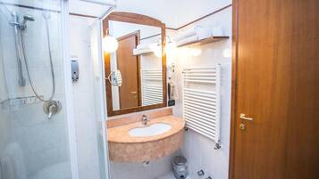 A bathroom with a glass shower enclosure, a sink with a mirror, and a towel rack.