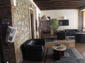 Una sala de estar con pared de piedra, sofás de cuero, una mesa de centro y un televisor.
