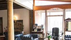 A spacious living area with leather sofas, a coffee table, and a large window with curtains. - Primotel (Brescia)