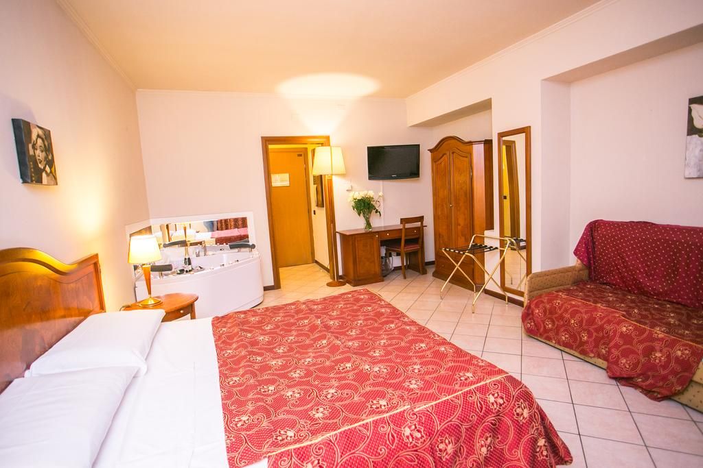 Een hotelkamer met een bed, een bureau met stoel, een televisie en een kledingkast.