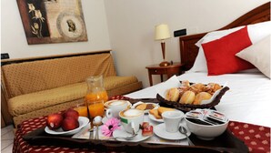 A neatly arranged breakfast tray with pastries, coffee, and fruit on a bed in a hotel room. - Primotel (Brescia)