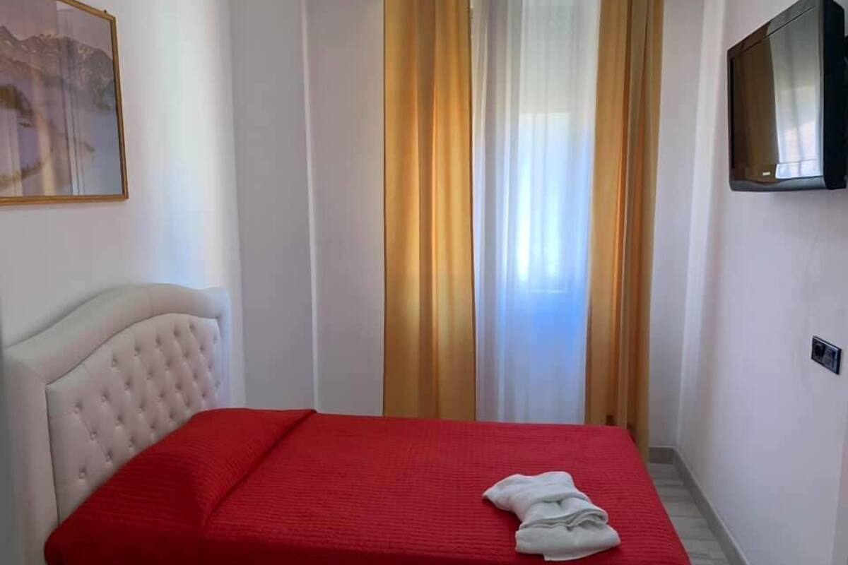 A hotel room with a bed, a television, and a painting on the wall.