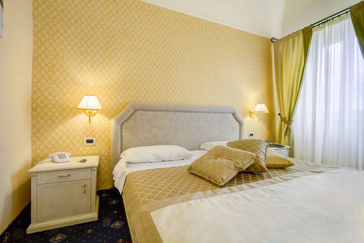 A hotel room with a bed, bedside tables, lamps, and a telephone.