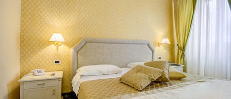 Una habitación de hotel con cama, mesitas de noche, lámparas y teléfono.
