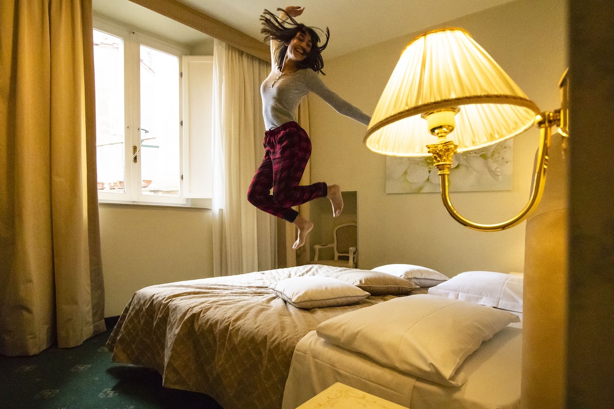 A room with a bed, a lamp, and a window with curtains.