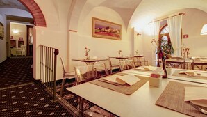 A hotel dining area with tables set for guests, clear glass chairs, and a patterned carpet. - Hotel La Locanda (Volterra)