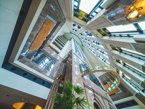 En atriumgård i flera våningar med en central, spiralformad trappa, glasräcken och en mängd olika arkitektoniska detaljer.