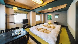Une chambre d’hôtel avec un lit, un bureau sur lequel se trouve un plateau avec divers objets, une télévision et une fenêtre avec des rideaux.