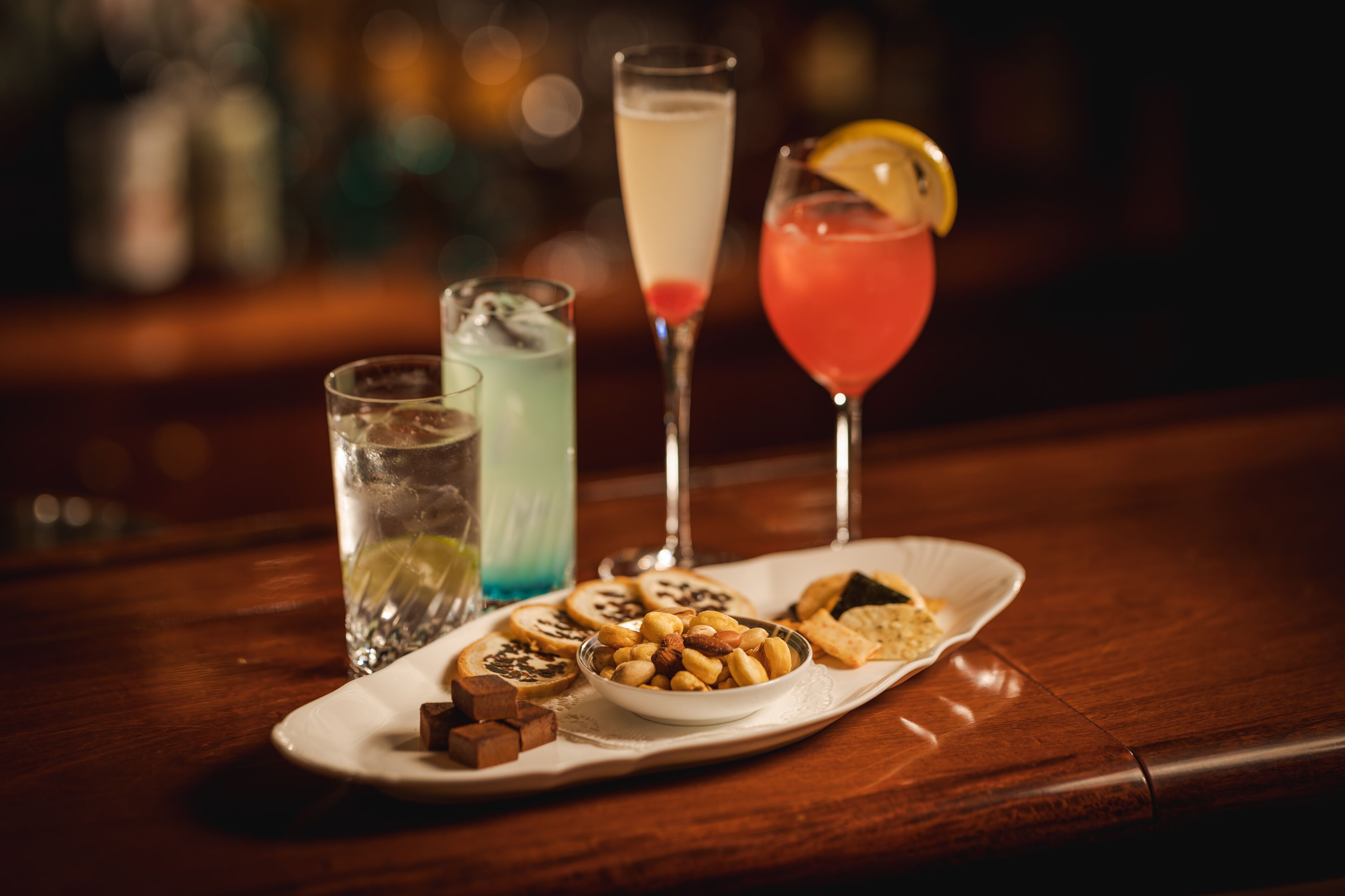 A tray with various drinks and snacks on a wooden table.