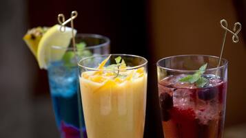 Three glasses of beverages with garnishes and straws.