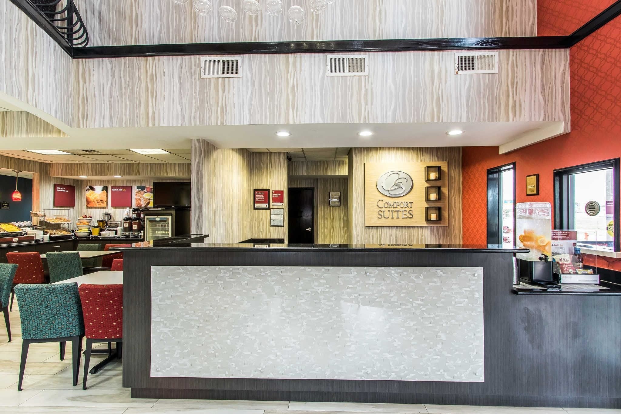 A hotel reception area with a modern design, including a reception desk, seating area, and a view of the dining section.