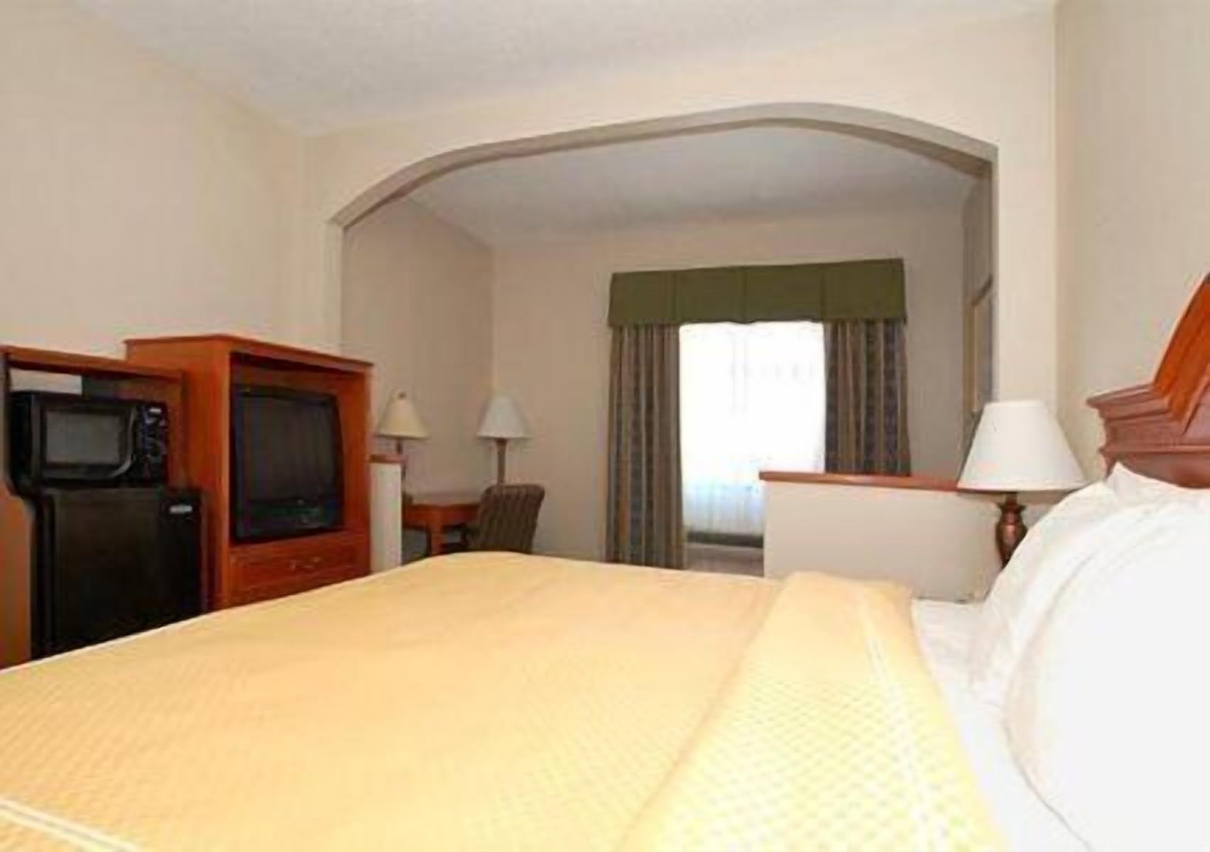 A hotel room with a bed, a television, a desk, and a chair.