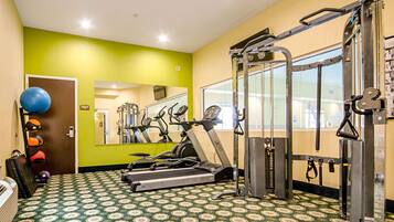 Un gimnasio con equipo de ejercicio, piso estampado y un espejo.