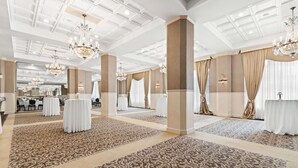 A spacious hotel lobby with ornate chandeliers, patterned carpet, and elegant drapery. - Genetti Hotel, SureStay Collection by Best Western (Williamsport)