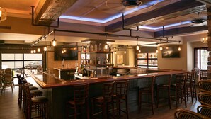 A bar area with stools, a bar counter, and hanging lights. - Genetti Hotel, SureStay Collection by Best Western (Williamsport)