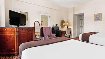 A hotel room with a large bed, a television, a desk with a computer, a chair, and a mirror.