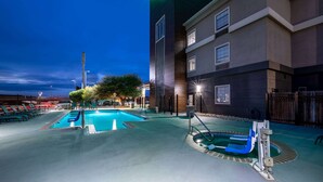 Ein Hotel mit Schwimmbecken, Rettungsschwimmerstation und gut beleuchteter Fassade.