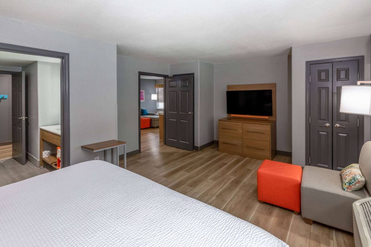 A hotel room with a bed, a TV, a desk, a chair, and a sofa.