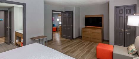 A hotel room with a bed, a TV, a desk, a chair, and a sofa.
