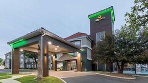 Ein Hotel mit Eingangsbereich, einem überdachten Gang, einem gut sichtbaren Schild und einem Pool im Hintergrund.