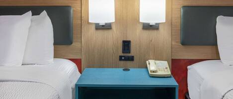 A hotel room with two beds, a blue nightstand, a telephone, and a wall-mounted light fixture.
