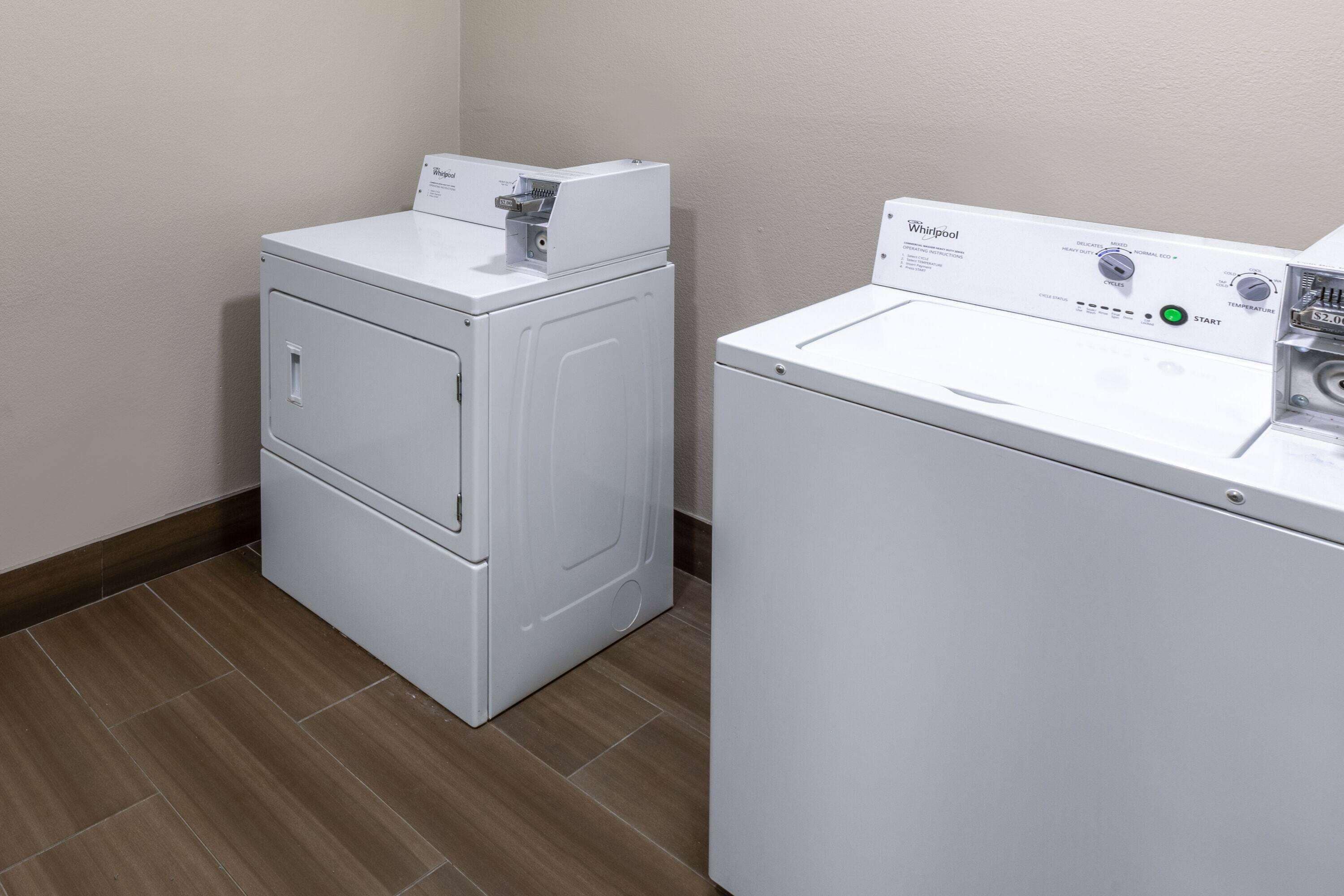 Un cuarto de lavandería con dos lavadoras y secadoras Whirlpool blancas.