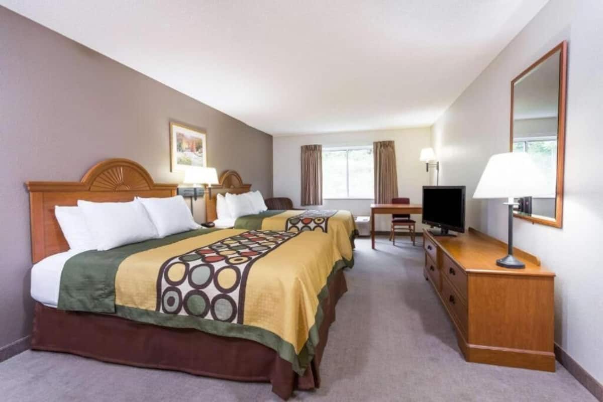 Ein Hotelzimmer mit zwei Betten, einem Schreibtisch, einem Fernseher und einem Schminktisch.