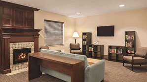 A living room with a fireplace, a sofa, a coffee table, a TV, and bookshelves. - Country Inn & Suites by Radisson, Dayton South, OH (Dayton)
