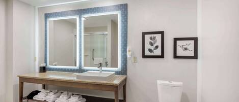A modern bathroom with a double sink vanity, a large mirror, and a toilet.
