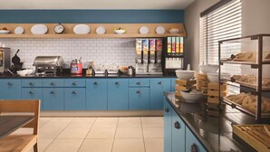 A modern kitchen with blue cabinets, a stainless steel refrigerator, and a breakfast bar with pastries. - Country Inn & Suites by Radisson, Dayton South, OH (Dayton)