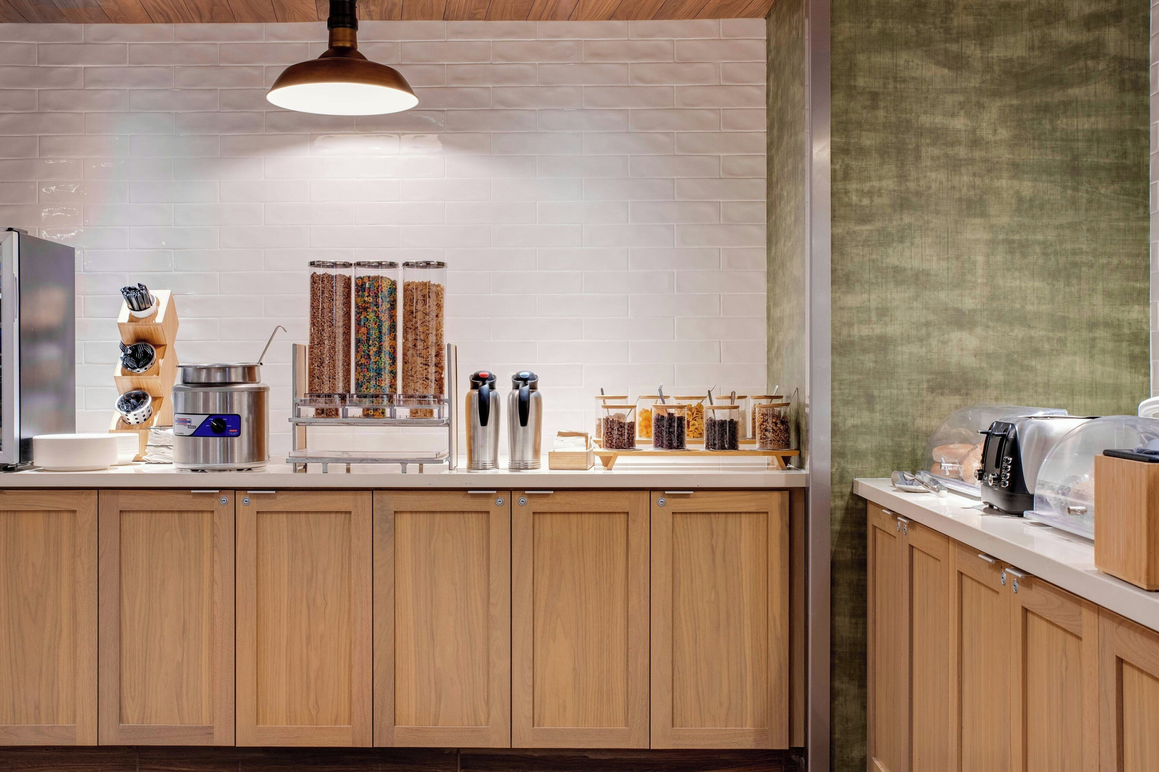 Una cocina moderna con armarios de madera, salpicadero de ladrillo y diferentes electrodomésticos y utensilios de cocina.
