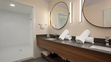 A modern bathroom with a shower, a sink, and two mirrors.