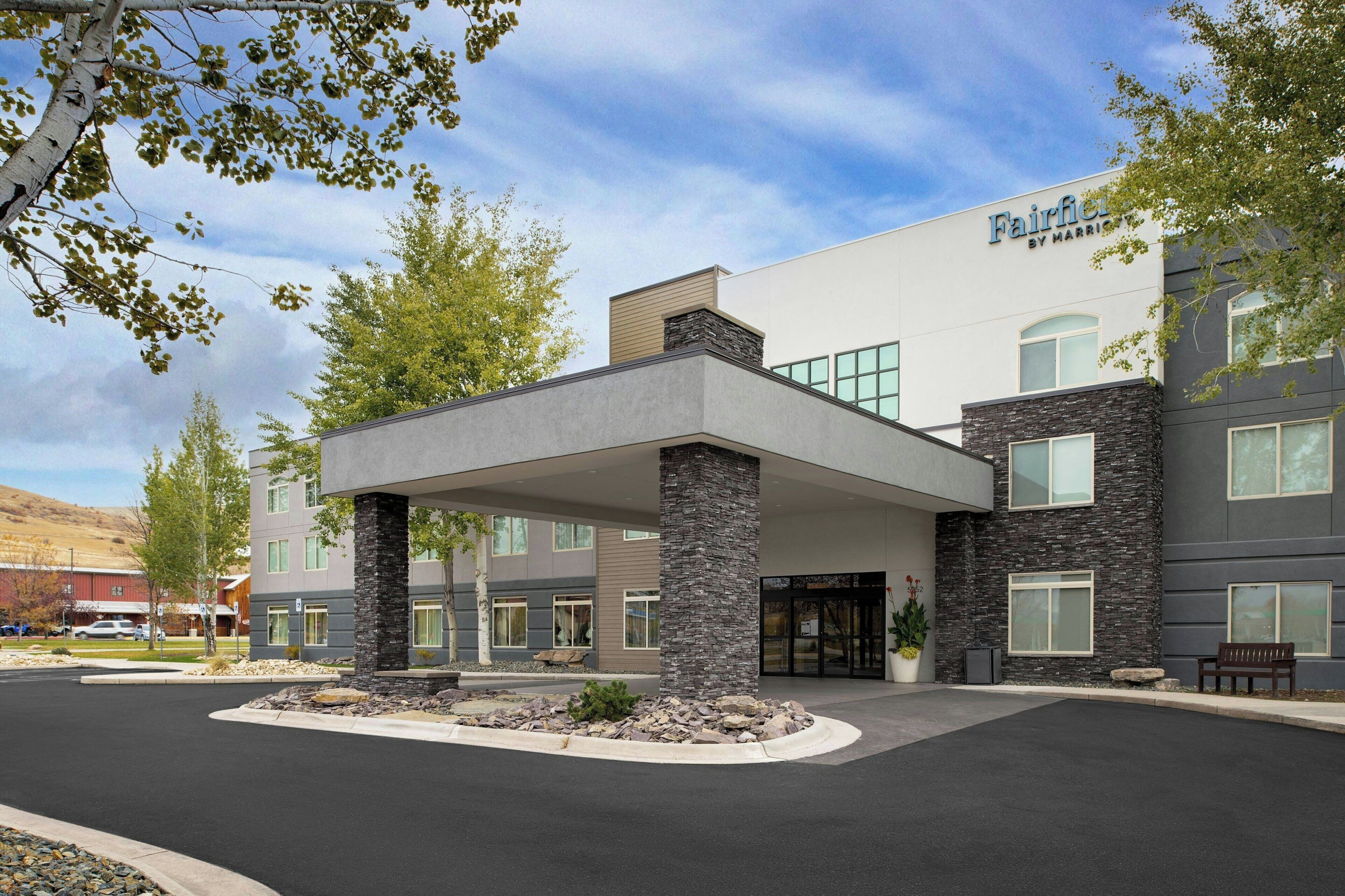 A Fairfield by Marriott hotel with a modern design, featuring a covered entrance, stone pillars, and a landscaped front yard.