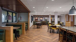 A modern restaurant with wooden flooring, green cushioned seating, and pendant lighting. - Fairfield by Marriott Inn & Suites Missoula Airport (Missoula)
