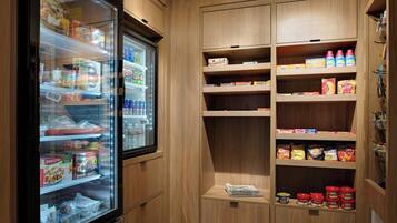 A kitchenette with a refrigerator stocked with food items, a microwave, and various kitchen appliances.