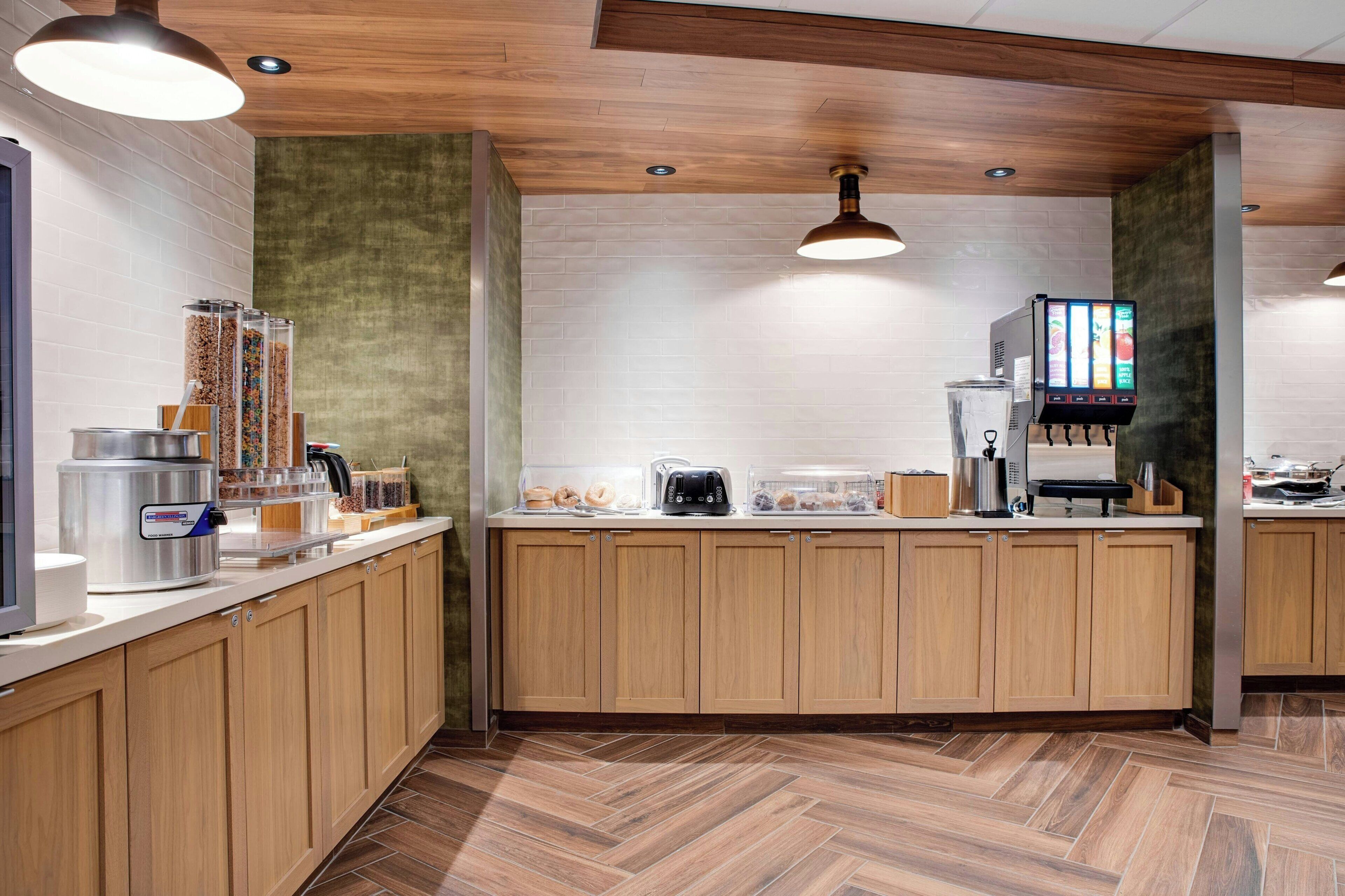 Una cocina moderna con armarios de madera, una máquina de café, un dispensador de alimentos y un menú digital.