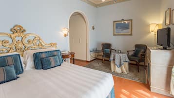 Una habitación de hotel con una cama grande, un escritorio, una silla, un televisor y un armario.