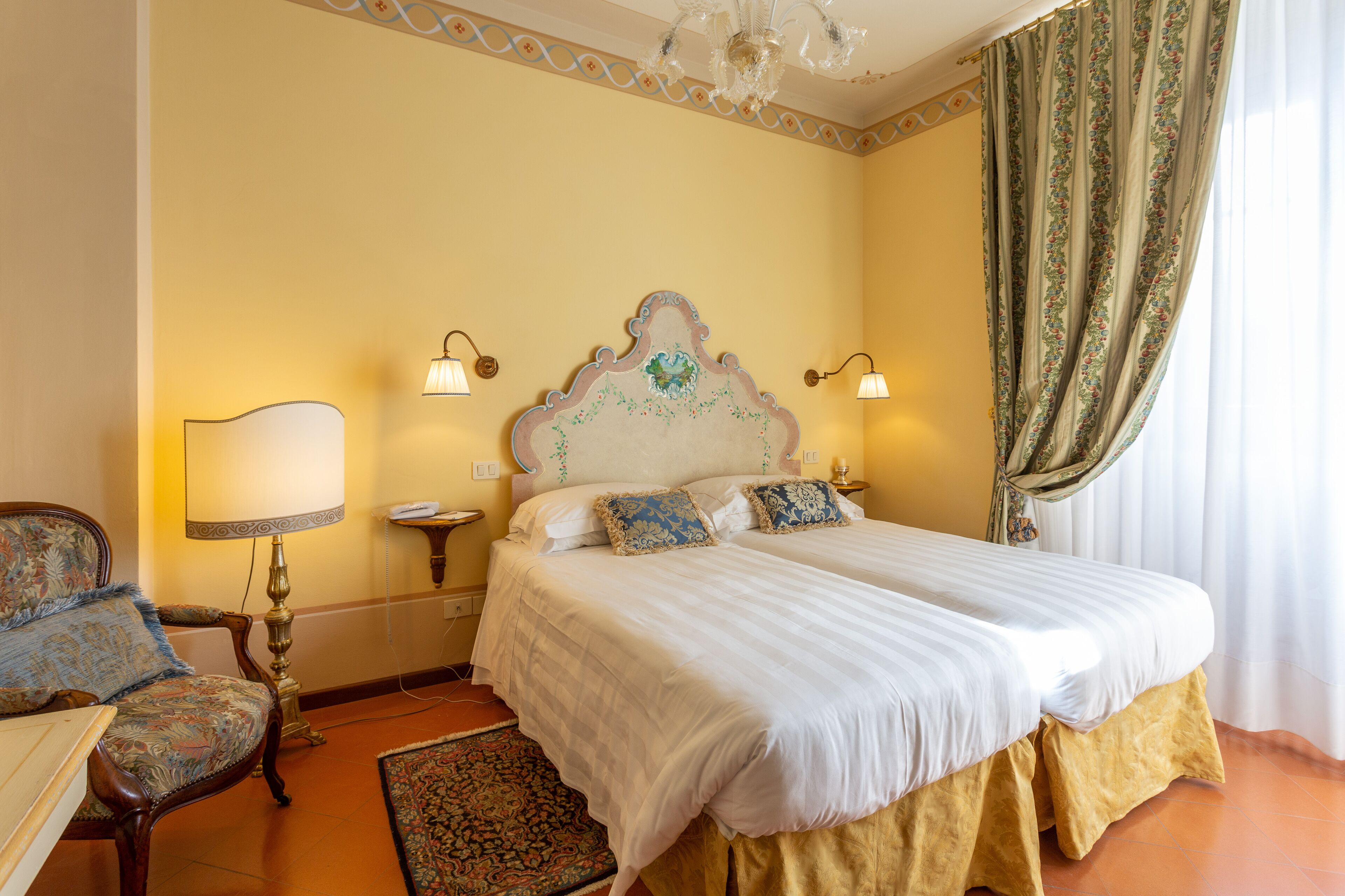 Habitación de hotel con una cama grande, una silla, una lámpara y un cabecero decorativo.