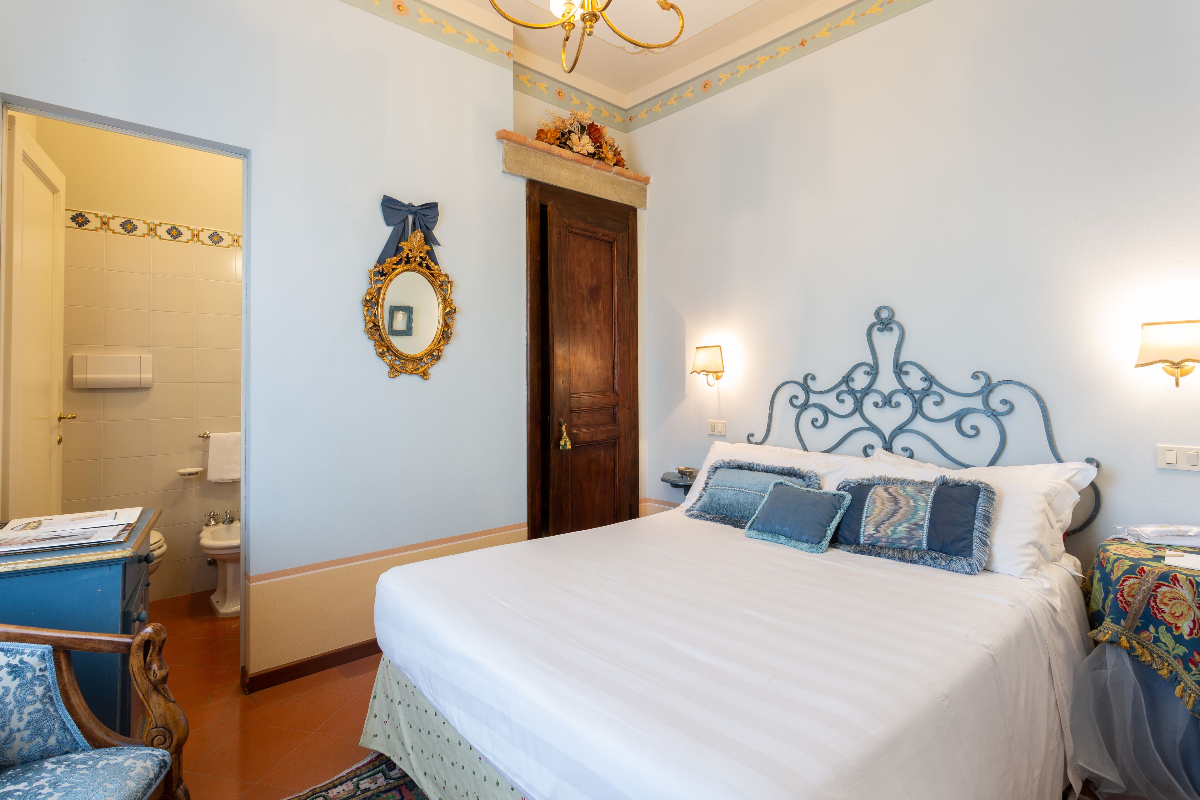 A bedroom with a bed, a dresser, a chair, a mirror, and a door.