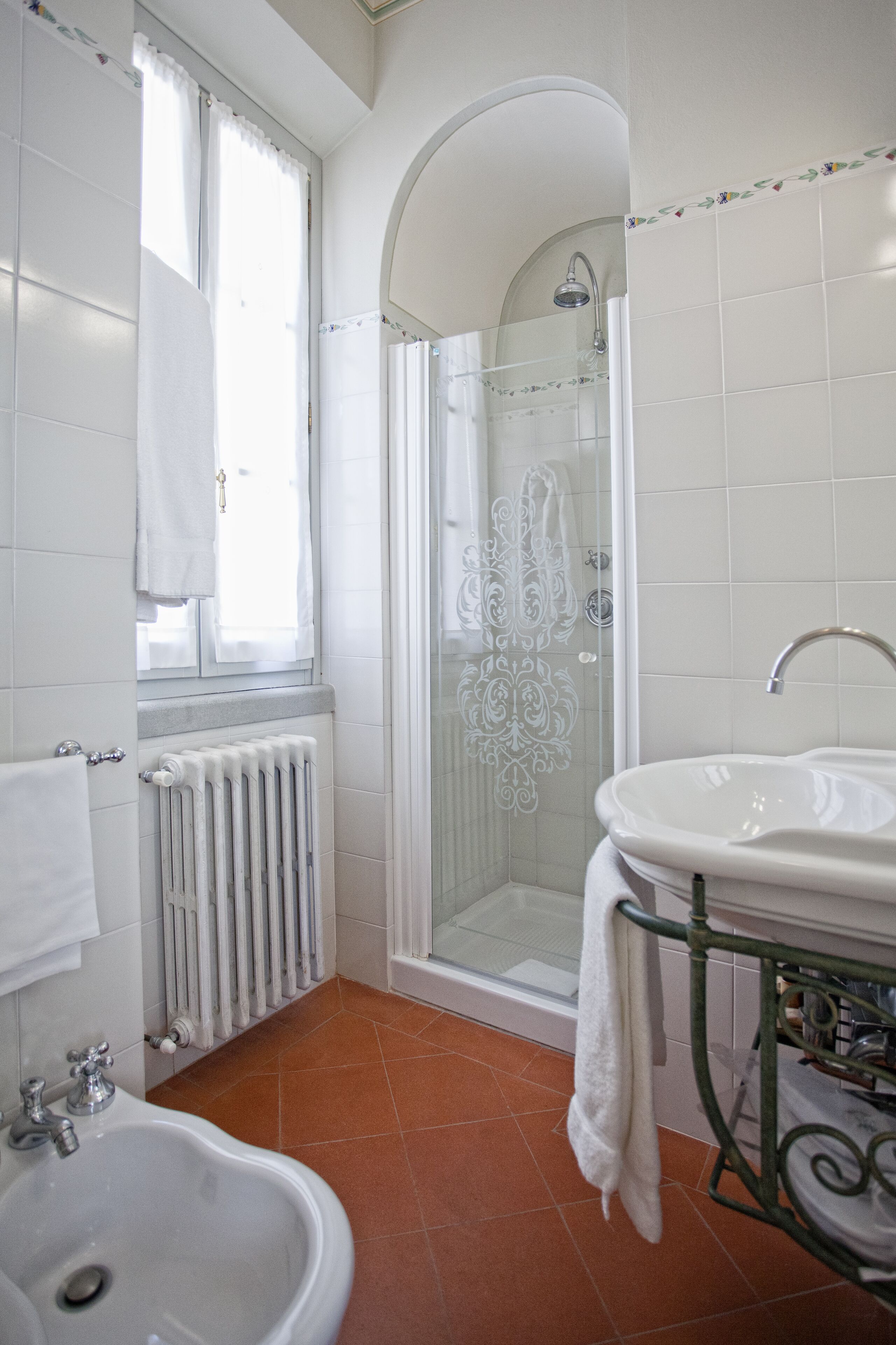 A bathroom with a shower, a sink, and a radiator.