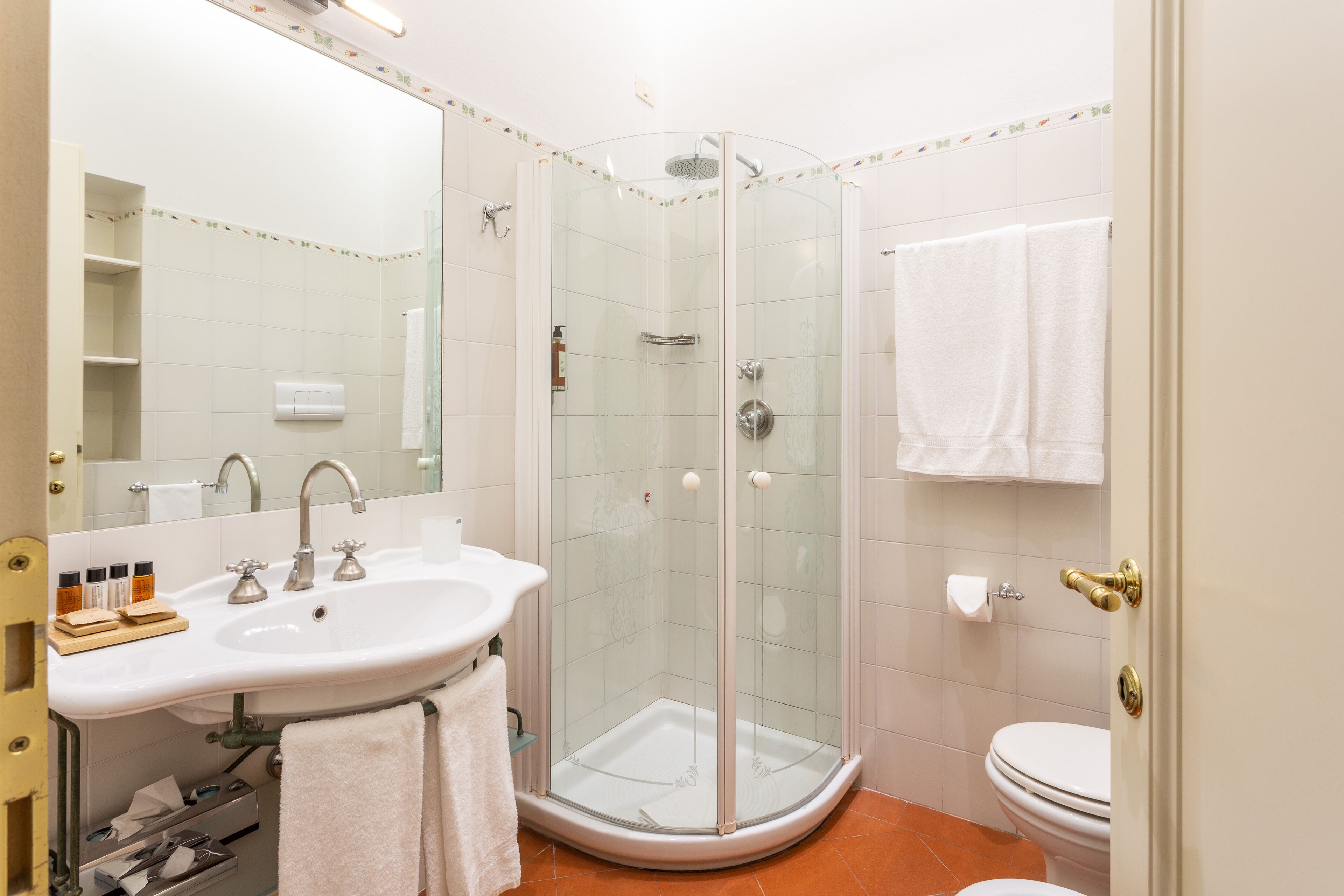 A modern bathroom with a glass-enclosed shower, a white sink, and a toilet.
