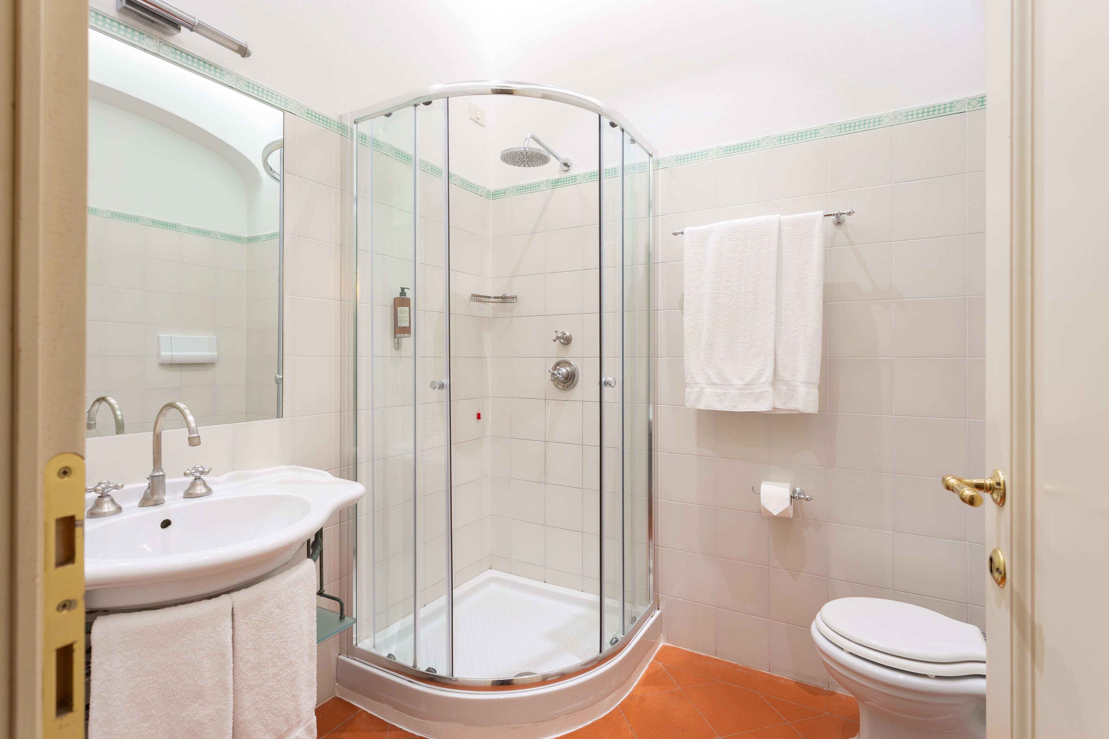 A bathroom with a glass-enclosed shower, a sink with a mirror, and a toilet.