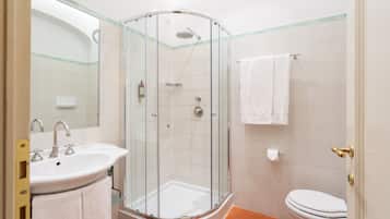 A bathroom with a glass-enclosed shower, a sink with a mirror, and a toilet.