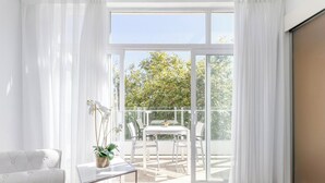 Una habitación luminosa con una mesa y sillas de vidrio, una planta en maceta y vistas a un balcón con mesa y sillas.