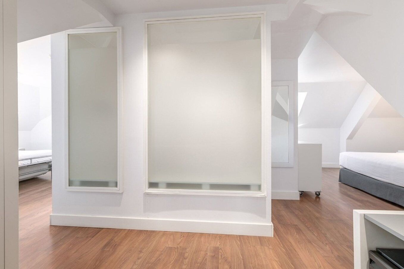 Un dormitorio moderno con cama estilo loft, vestidor y tragaluz.