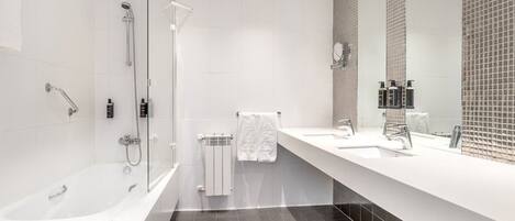 A modern bathroom with a bathtub, shower, and a large mirror.
