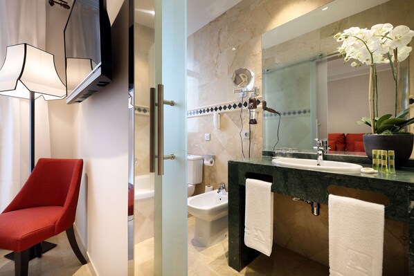 A modern bathroom with a red chair, a large mirror, a sink, and a shower.