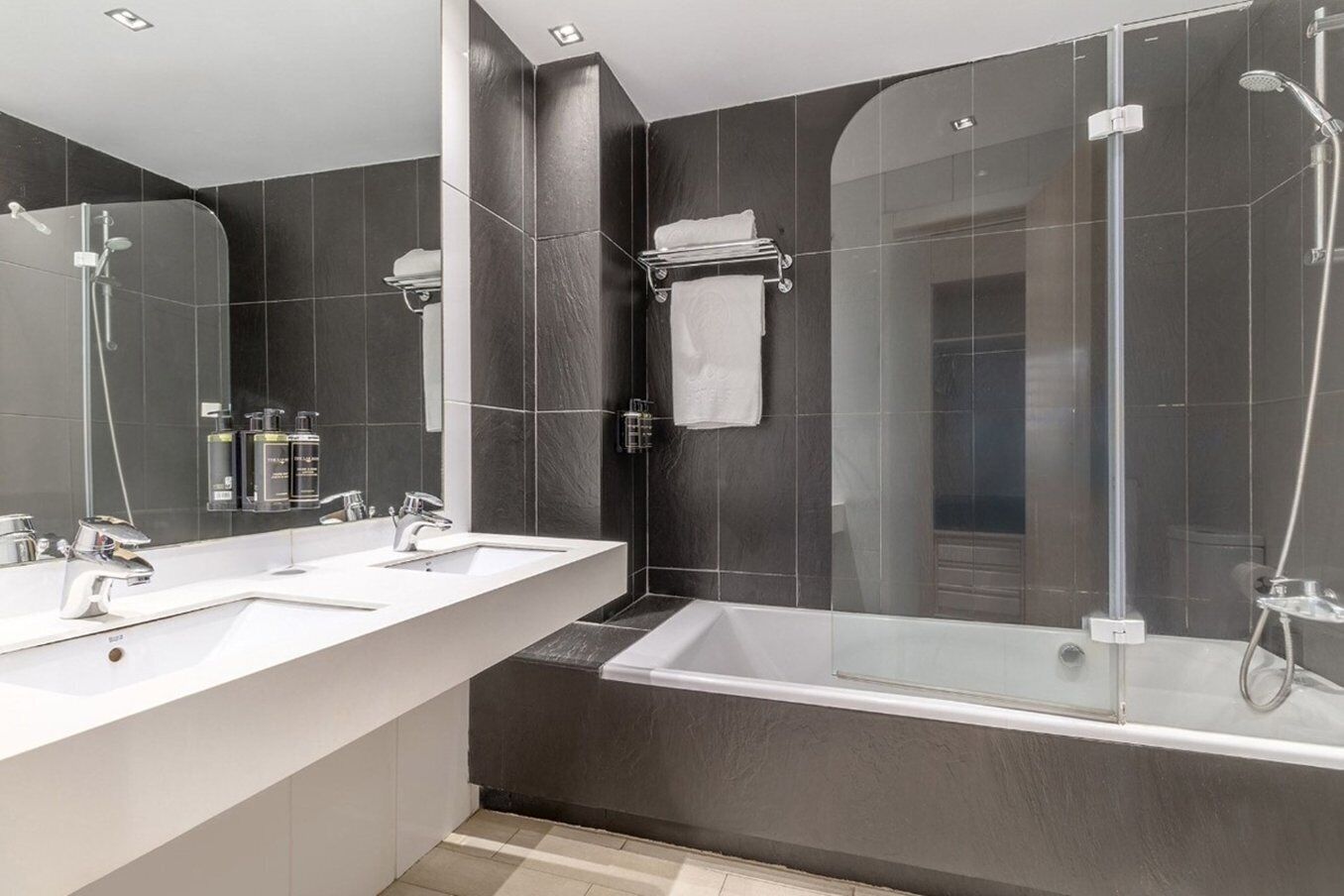 Ein modernes Badezimmer mit zwei Waschbecken, einer großen Badewanne und einer gläsernen Dusche.