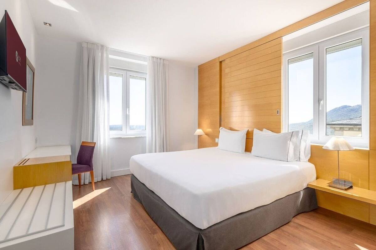 Une chambre d’hôtel avec un grand lit, un bureau, une chaise et un téléviseur.